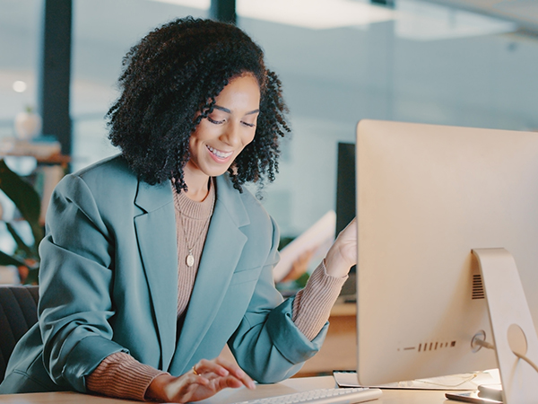 African American Woman sitting at desk typing on a keyboard.