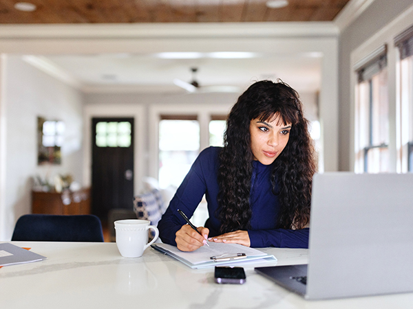 Women sitting on kitchen counter working on laptop computer